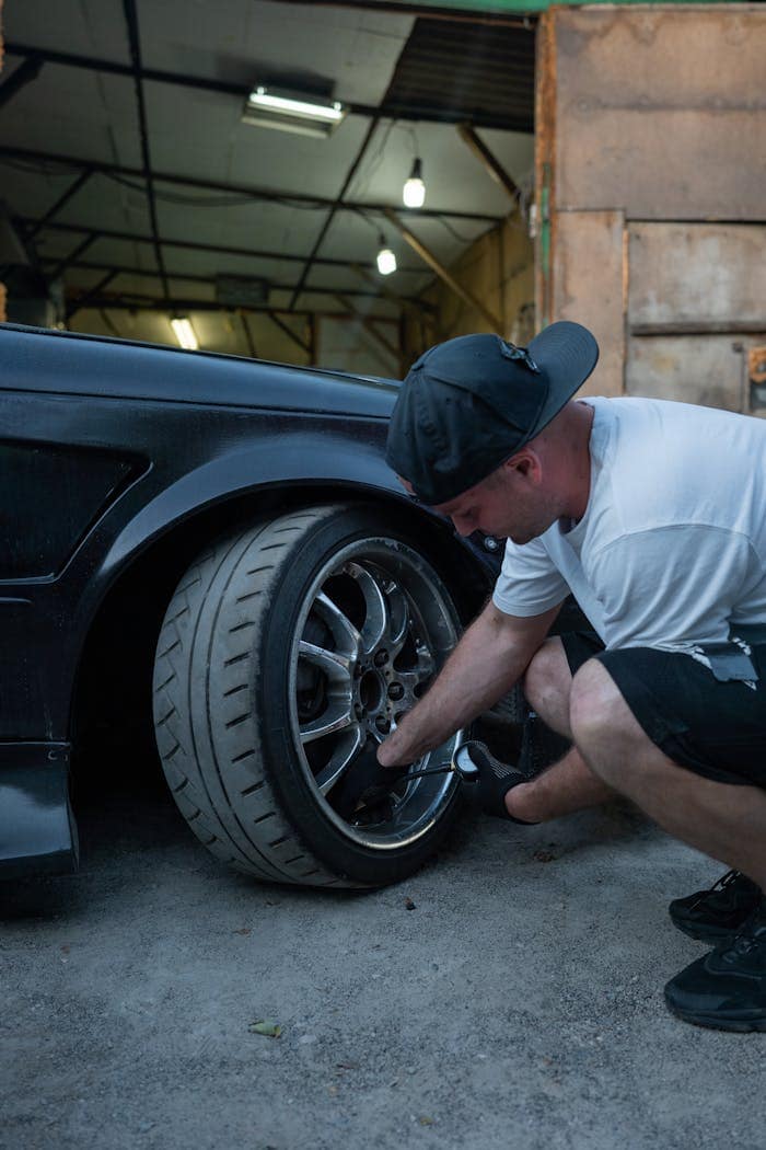 The Art of Drawing Readers In: Your attractive post title goes here A man changes a car tire in a garage workshop, showcasing automotive maintenance.